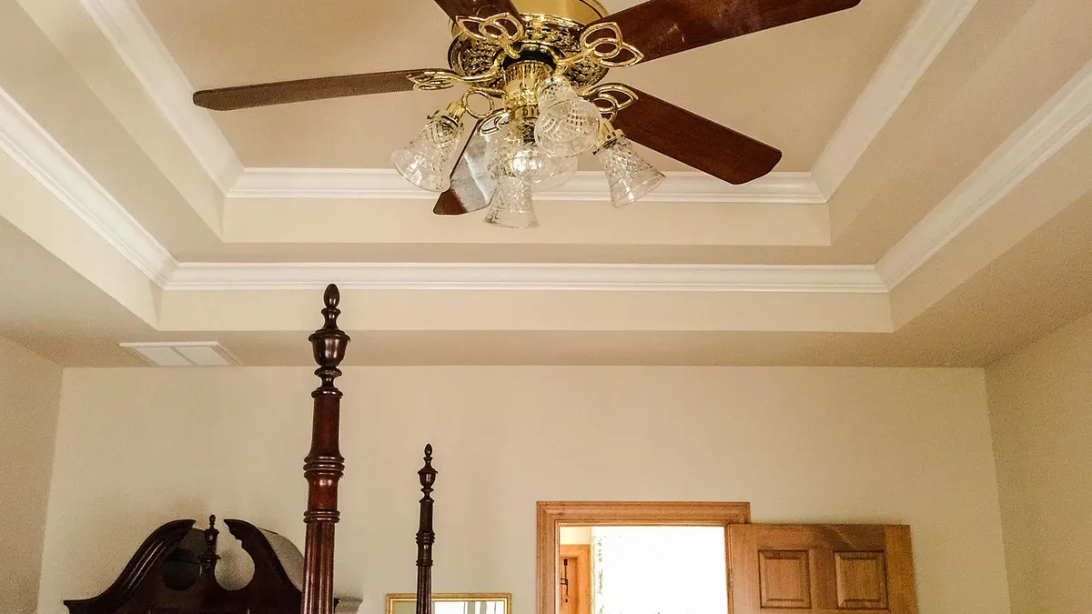 Ventilador de teto com luminária dourada em forro rebaixado